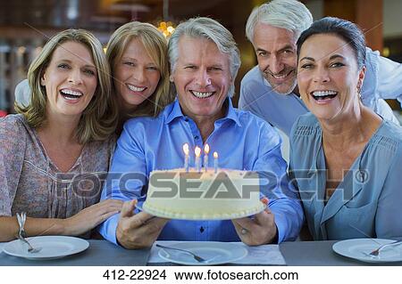 Picture - Portrait of smiling mature men and women with birthday cake. Fotosearch