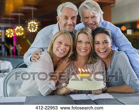 Stock Image - Portrait of smiling mature men and women with birthday cake. Fotosearch