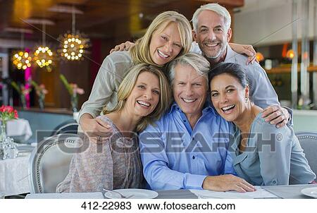 Portrait of smiling mature men and women sitting at restaurant table View Large Photo Image Stock Image - Portrait of smiling mature men and women sitting at restaurant table. Fotosearch