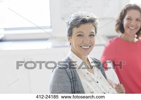 Portrait of smiling mature businesswoman with colleague in background View Large Photo Image Stock Photography - Portrait of smiling mature businesswoman with colleague in background . Fotosearch