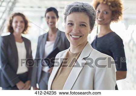 Portrait of smiling mature businesswoman with office team in background View Large Photo Image Stock Photography - Portrait of smiling mature businesswoman with office team in background. Fotosearch