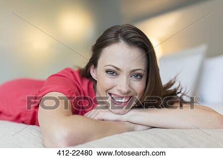 Portrait of smiling mid-adult woman wearing red dress lying on bed in bedroom View Large Photo Image Stock Image - Portrait of smiling mid-adult woman wearing red dress lying on bed in bedroom. Fotosearch