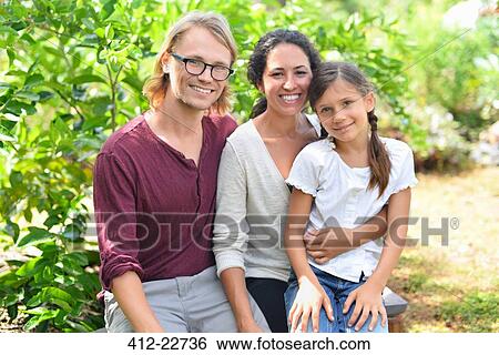 Portrait of smiling parents with daughter sitting on bench in garden View Large Photo Image Stock Photograph - Portrait of smiling parents with daughter sitting on bench in garden. Fotosearch