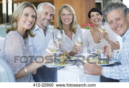 Portrait of smiling people toasting with white wine in restaurant View Large Photo Image Stock Image - Portrait of smiling people toasting with white wine in restaurant. Fotosearch