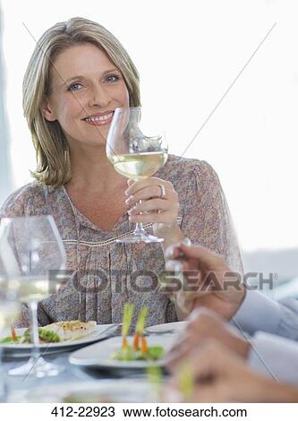 Portrait of smiling woman holding glass of white wine at restaurant table View Large Photo Image Stock Image - Portrait of smiling woman holding glass of white wine at restaurant table. Fotosearch