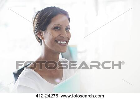 Portrait of smiling woman holding documents in office View Large Photo Image Stock Photograph - Portrait of smiling woman holding documents in office. Fotosearch