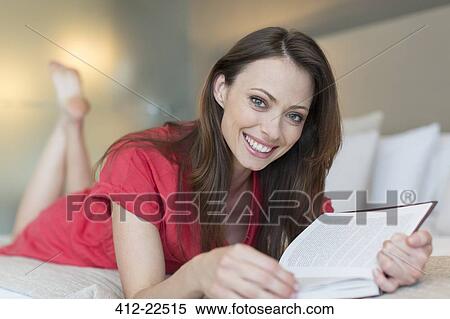 Portrait of smiling woman lying on bed and reading book View Large Photo Image Stock Photography - Portrait of smiling woman lying on bed and reading book. Fotosearch