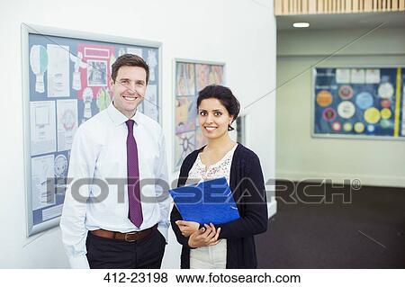 Stock Photo - Portrait of tow smiling teachers standing in school corridor. Fotosearch