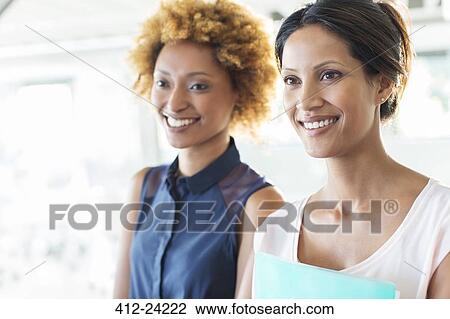 Stock Image - Portrait of two smiling businesswomen in office. Fotosearch