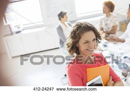 Stock Photo - Portrait of woman with tablet in office, colleagues in background. Fotosearch