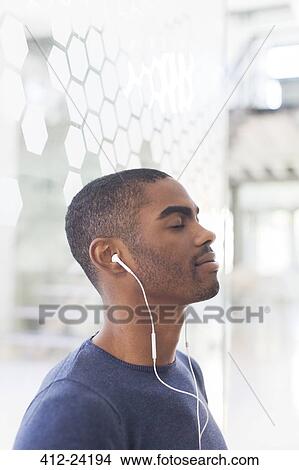 Portrait of young businessman listening to music on earphones View Large Photo Image Picture - Portrait of young businessman listening to music on earphones. Fotosearch