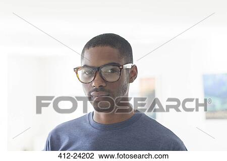 Portrait of young businessman wearing glasses standing in office View Large Photo Image Stock Image - Portrait of young businessman wearing glasses standing in office. Fotosearch