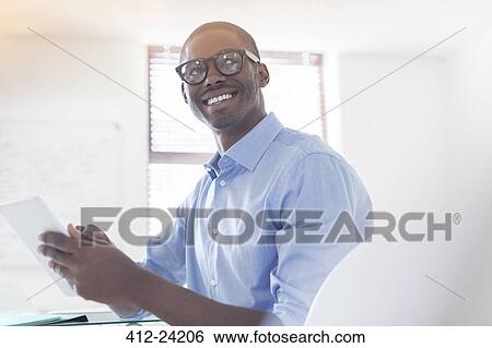 Portrait of young businessman wearing glasses and blue shirt holding digital tablet in office View Large Photo Image Stock Photograph - Portrait of young businessman wearing glasses and blue shirt holding digital tablet in office. Fotosearch