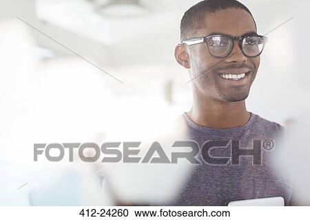 Portrait of young smiling businessman wearing glasses in office View Large Photo Image Stock Image - Portrait of young smiling businessman wearing glasses in office. Fotosearch