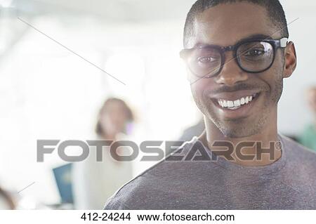 Portrait of young smiling man wearing glasses, woman in background View Large Photo Image Picture - Portrait of young smiling man wearing glasses, woman in background. Fotosearch