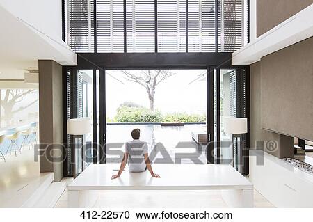 Rear view of man sitting on table and looking at swimming pool through open patio door View Large Photo Image Stock Image - Rear view of man sitting on table and looking at swimming pool through open patio door. Fotosearch