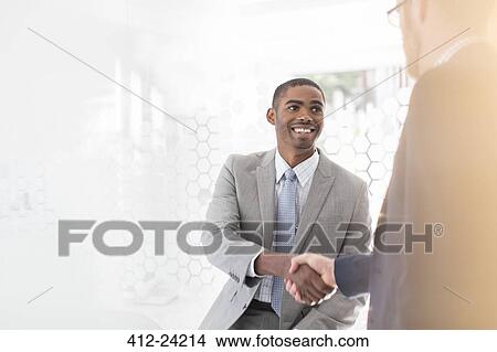 Picture - Smiling businessmen shaking hands in office. Fotosearch
