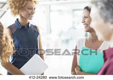 Stock Image - Smiling businesswomen having meeting in office. Fotosearch