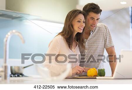 Smiling couple cutting bell peppers and looking at laptop in modern kitchen View Large Photo Image Stock Photography - Smiling couple cutting bell peppers and looking at laptop in modern kitchen. Fotosearch
