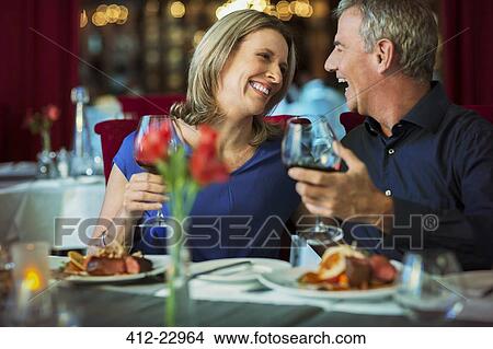 Smiling happy mature couple looking at each other and holding glasses with red wine in restaurant View Large Photo Image Picture - Smiling happy mature couple looking at each other and holding glasses with red wine in restaurant. Fotosearch