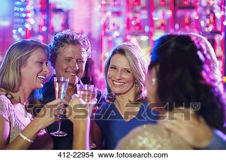 Smiling mature people toasting with champagne flutes in nightclub View Large Photo Image Picture - Smiling mature people toasting with champagne flutes in nightclub. Fotosearch