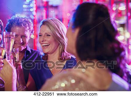 Smiling mature people toasting with champagne flutes in nightclub View Large Photo Image Stock Image - Smiling mature people toasting with champagne flutes in nightclub. Fotosearch