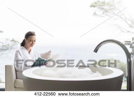 Smiling woman in bathrobe reading book in bathroom View Large Photo Image Stock Image - Smiling woman in bathrobe reading book in bathroom. Fotosearch