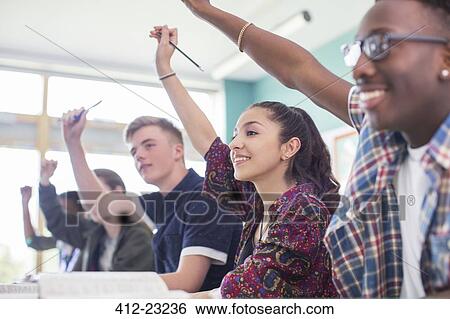 Students sitting in classroom during lesson, smiling and raising hands View Large Photo Image Stock Photograph - Students sitting in classroom during lesson, smiling and raising hands. Fotosearch