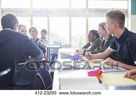 Stock Image - Students talking in classroom during lesson. Fotosearch