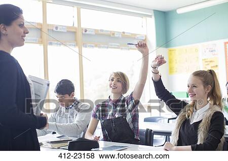 Students with their teacher in classroom, smiling and raising arms View Large Photo Image Stock Photo - Students with their teacher in classroom, smiling and raising arms. Fotosearch