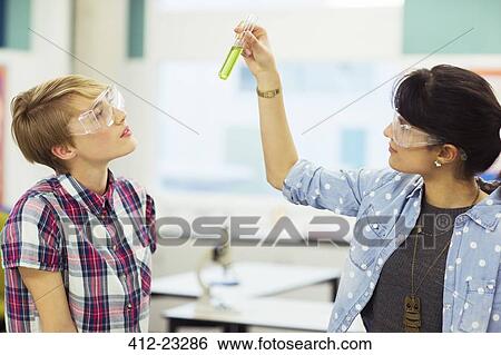 Teacher and student during chemistry lesson, wearing protective eyewear and looking at test tube with green liquid View Large Photo Image Stock Photograph - Teacher and student during chemistry lesson, wearing protective eyewear and looking at test tube with green liquid. Fotosearch