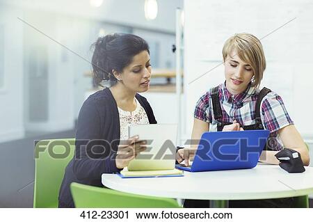 Teacher and student sitting together with digital tablet and laptop View Large Photo Image Stock Image - Teacher and student sitting together with digital tablet and laptop. Fotosearch