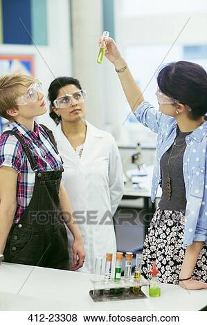 Teacher and students during chemistry lesson, wearing protective eyewear and looking at test tube with green liquid View Large Photo Image Stock Photo - Teacher and students during chemistry lesson, wearing protective eyewear and looking at test tube with green liquid. Fotosearch