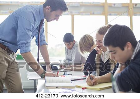Teacher helping his students in classroom View Large Photo Image Stock Image - Teacher helping his students in classroom. Fotosearch