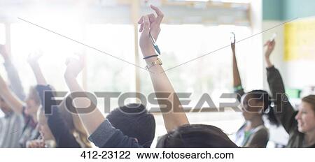 Teenage students with arms raised in classroom View Large Photo Image Stock Image - Teenage students with arms raised in classroom. Fotosearch