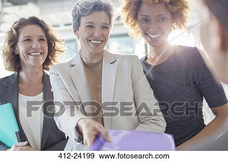 Three smiling businesswomen holding documents View Large Photo Image Stock Photo - Three smiling businesswomen holding documents. Fotosearch