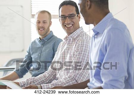 Three smiling men working together in office View Large Photo Image Stock Photo - Three smiling men working together in office. Fotosearch