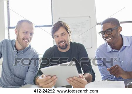Three smiling men working with digital tablet in office View Large Photo Image Stock Image - Three smiling men working with digital tablet in office. Fotosearch