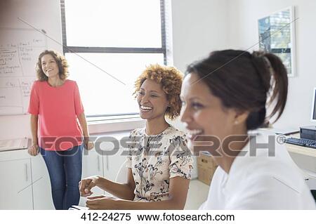 Stock Photography - Three women laughing during meeting in office. Fotosearch