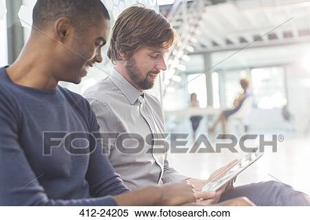 Two smiling businessmen using digital tablet in office View Large Photo Image Stock Photography - Two smiling businessmen using digital tablet in office. Fotosearch