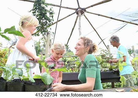 Picture - Two women working in greenhouse with girls. Fotosearch