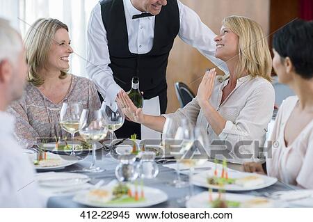 Waiter offering wine to female client at restaurant table, woman refusing View Large Photo Image Stock Photography - Waiter offering wine to female client at restaurant table, woman refusing. Fotosearch