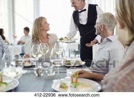 Waiter serving fancy dish to woman sitting at restaurant table View Large Photo Image Stock Photograph - Waiter serving fancy dish to woman sitting at restaurant table. Fotosearch