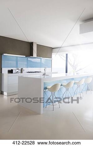 Stock Photo - White and clean modern kitchen with stools at kitchen island. Fotosearch