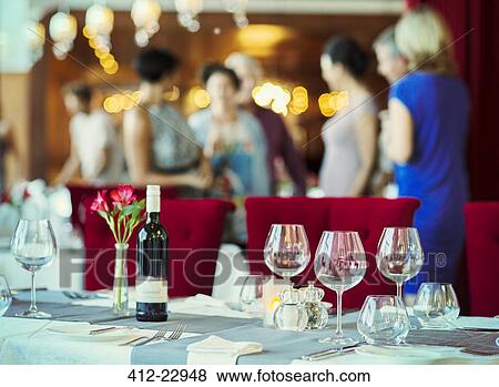 Wineglasses and bottle of red wine on table in restaurant, people in background View Large Photo Image Stock Photo - Wineglasses and bottle of red wine on table in restaurant, people in background. Fotosearch