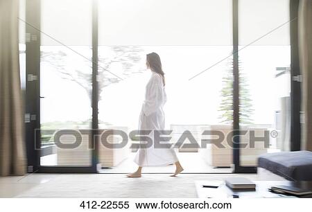 Stock Photography - Woman in bathrobe walking through living room. Fotosearch