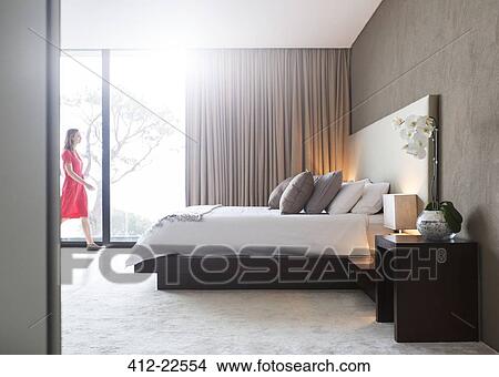 Woman in red dress walking through modern bedroom View Large Photo Image Picture - Woman in red dress walking through modern bedroom. Fotosearch