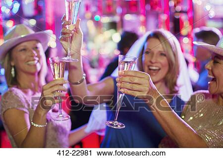 Stock Image - Women toasting with champagne flutes at bachelorette party. Fotosearch