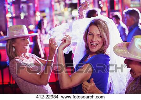 Picture - Women wearing hats dancing at bachelorette party. Fotosearch