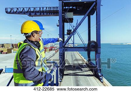 Worker and businessman examining cargo crane at waterfront View Large Photo Image Stock Photography - Worker and businessman examining cargo crane at waterfront. Fotosearch
